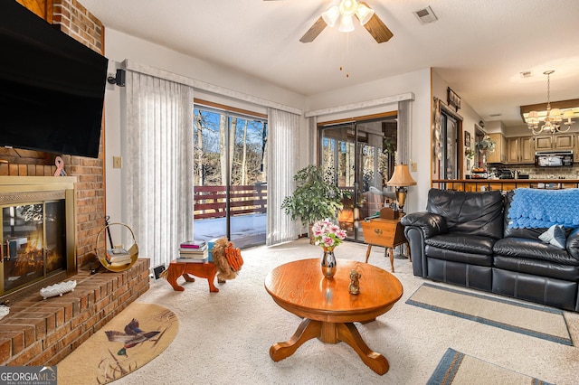 living room with ceiling fan with notable chandelier and a fireplace