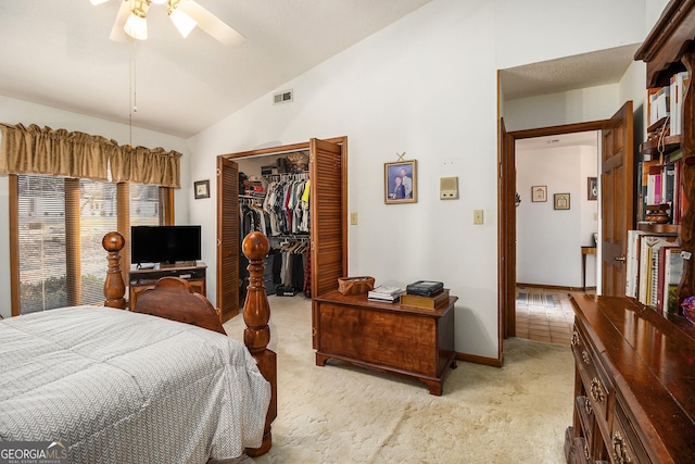 carpeted bedroom with ceiling fan, a walk in closet, a closet, and vaulted ceiling