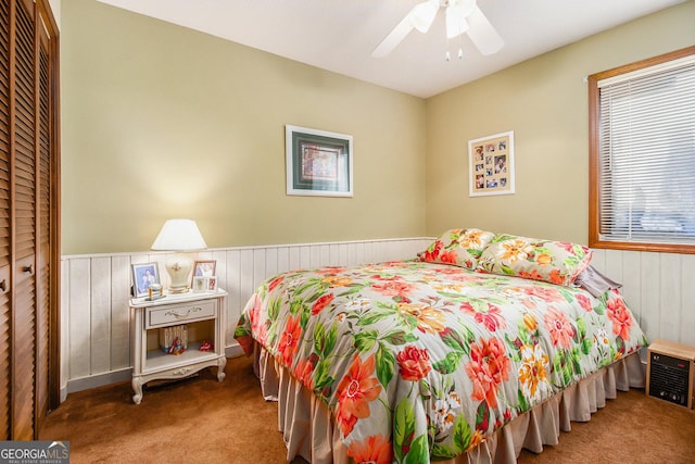 bedroom featuring wood walls, ceiling fan, a closet, and carpet