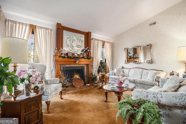 living room featuring a tile fireplace, carpet, and vaulted ceiling