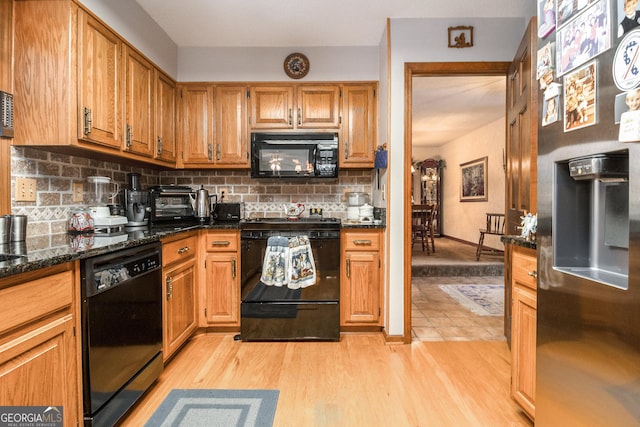 kitchen with backsplash, dark stone countertops, black appliances, and light hardwood / wood-style floors