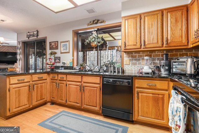 kitchen with kitchen peninsula, dishwasher, tasteful backsplash, light wood-type flooring, and dark stone counters