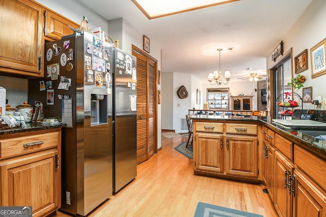 kitchen featuring kitchen peninsula, pendant lighting, stainless steel refrigerator with ice dispenser, light wood-type flooring, and ceiling fan with notable chandelier