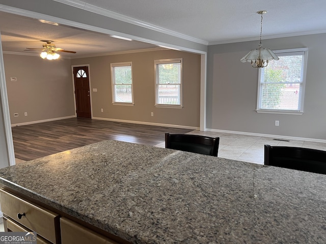 kitchen featuring ceiling fan with notable chandelier, ornamental molding, a textured ceiling, and decorative light fixtures