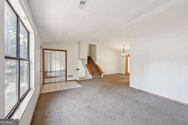 carpeted empty room featuring vaulted ceiling, a chandelier, and a textured ceiling