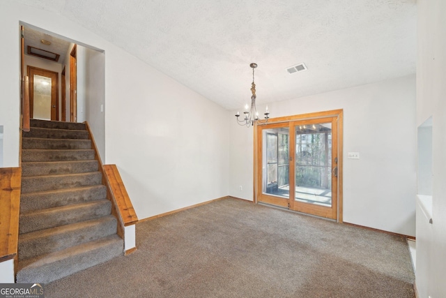 carpeted empty room with a notable chandelier and a textured ceiling