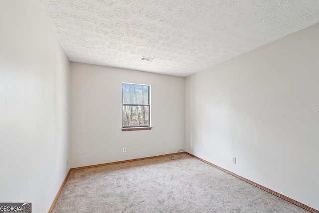 empty room featuring a textured ceiling and carpet