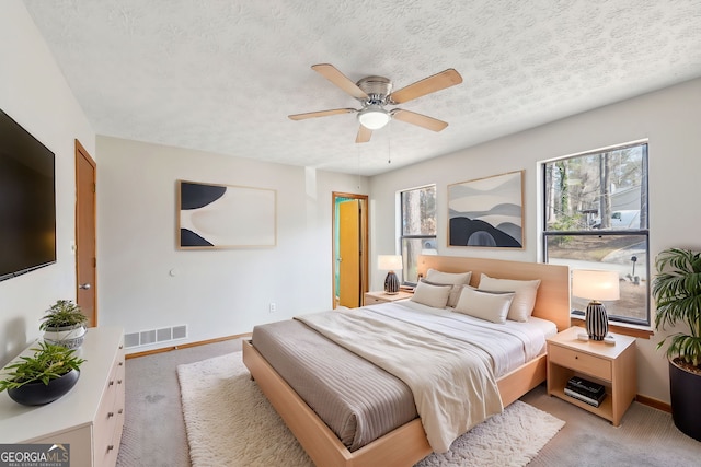 carpeted bedroom with ceiling fan and a textured ceiling