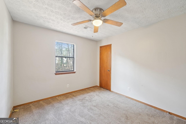 spare room with a textured ceiling, ceiling fan, and light colored carpet