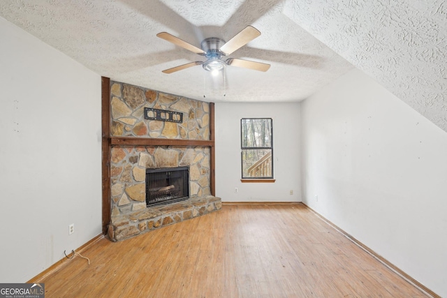 unfurnished living room featuring ceiling fan, a fireplace, a textured ceiling, and hardwood / wood-style floors