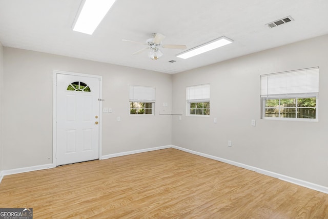 empty room featuring ceiling fan, a wealth of natural light, and light hardwood / wood-style flooring