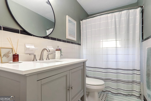 bathroom with tasteful backsplash, vanity, toilet, and tile walls