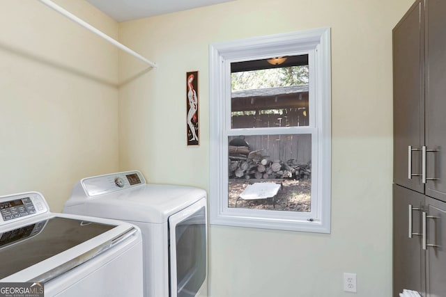 clothes washing area with cabinets and washer and clothes dryer