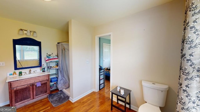 bathroom featuring hardwood / wood-style flooring, vanity, curtained shower, and toilet