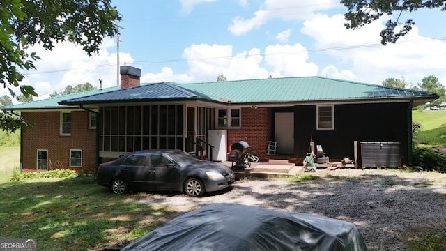 rear view of house featuring a yard and a sunroom