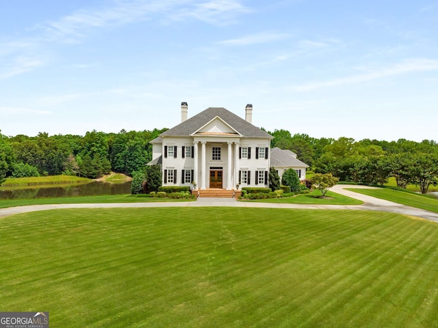 neoclassical / greek revival house featuring a water view and a front lawn