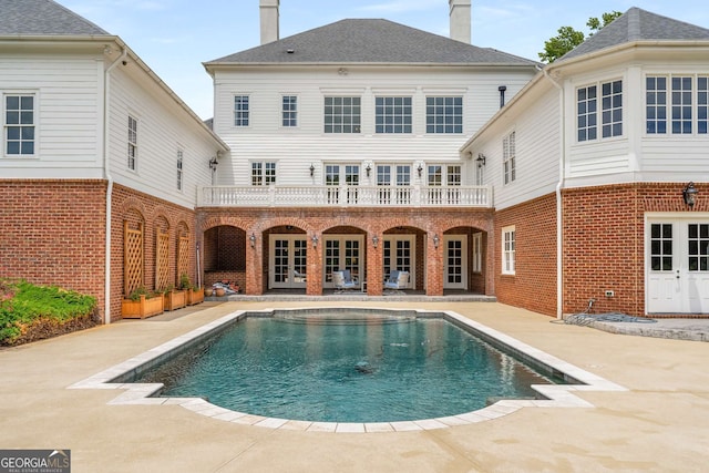 back of property with a patio area, a balcony, and french doors