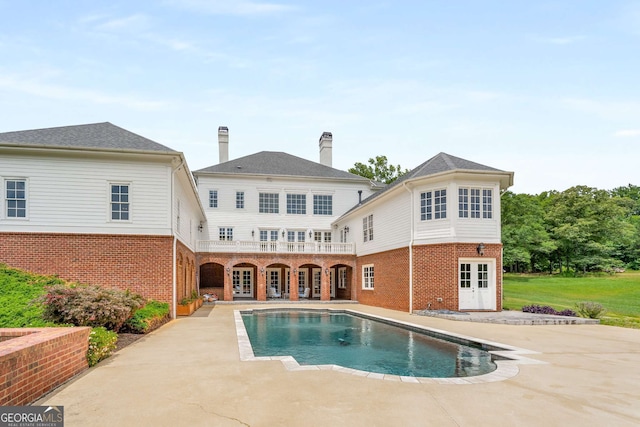 rear view of house featuring french doors, a balcony, and a patio