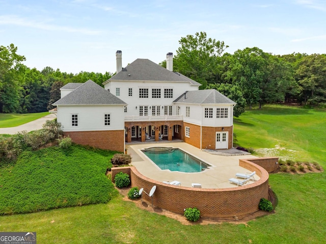 rear view of property featuring a lawn, a jacuzzi, and a patio