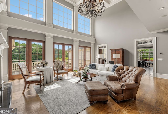 living room with french doors, a towering ceiling, a wealth of natural light, and a notable chandelier