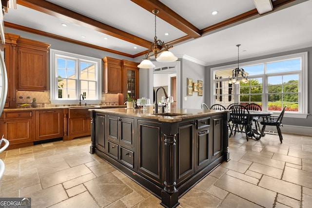 kitchen with sink, an island with sink, a chandelier, decorative light fixtures, and ornamental molding