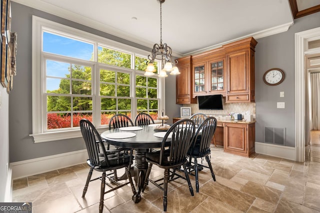 dining area featuring crown molding, a wealth of natural light, and an inviting chandelier