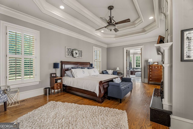 bedroom with wood-type flooring, a raised ceiling, ceiling fan, and crown molding