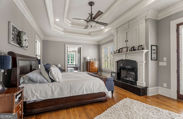 bedroom with a raised ceiling, ceiling fan, light hardwood / wood-style flooring, and ornamental molding