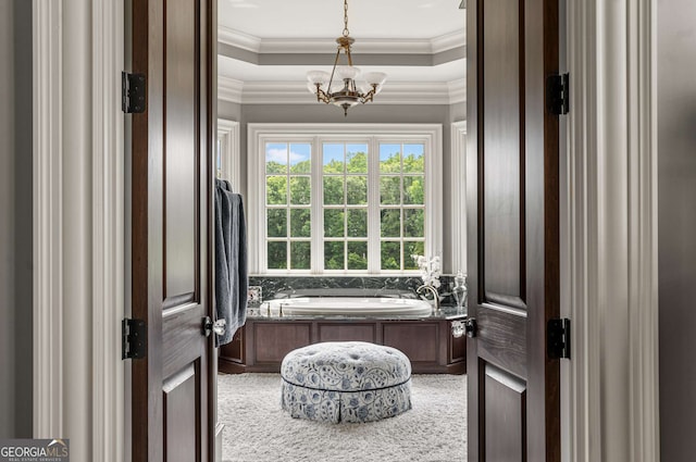 bathroom featuring a tray ceiling, a tub, ornamental molding, and a notable chandelier