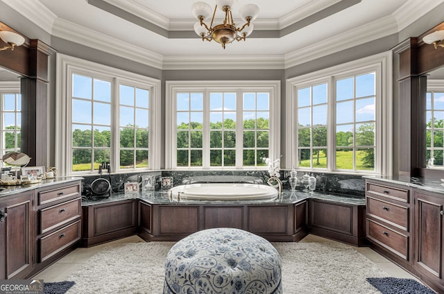 bathroom with a chandelier, a tray ceiling, a bathtub, and ornamental molding