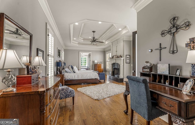 bedroom featuring hardwood / wood-style floors, ceiling fan, a raised ceiling, and crown molding