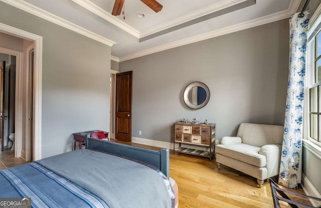 bedroom with a raised ceiling, ceiling fan, crown molding, and wood-type flooring