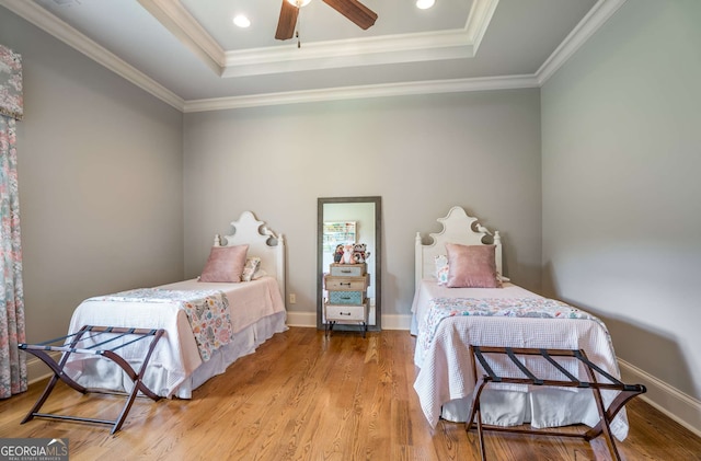 bedroom featuring a tray ceiling, ceiling fan, wood-type flooring, and ornamental molding