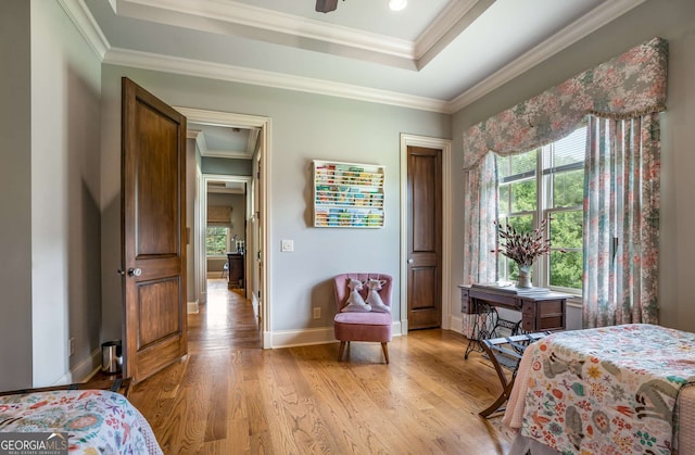 bedroom with ornamental molding, a tray ceiling, and light hardwood / wood-style flooring