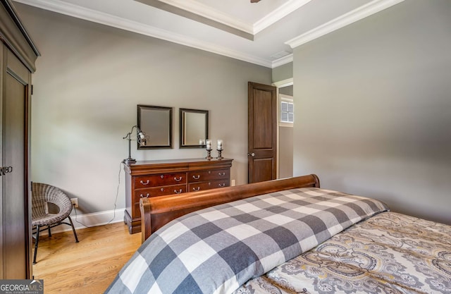 bedroom featuring a raised ceiling, light wood-type flooring, and ornamental molding