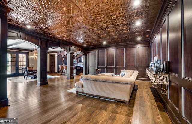 interior space with decorative columns, dark wood-type flooring, wooden walls, and a chandelier