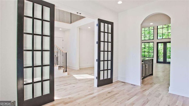 interior space featuring a high ceiling, light hardwood / wood-style flooring, and french doors