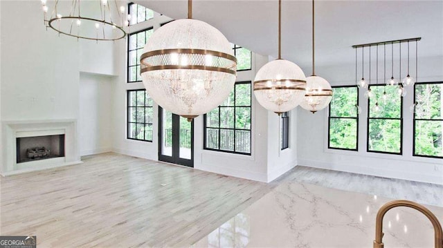 unfurnished living room featuring a healthy amount of sunlight, a chandelier, and light wood-type flooring