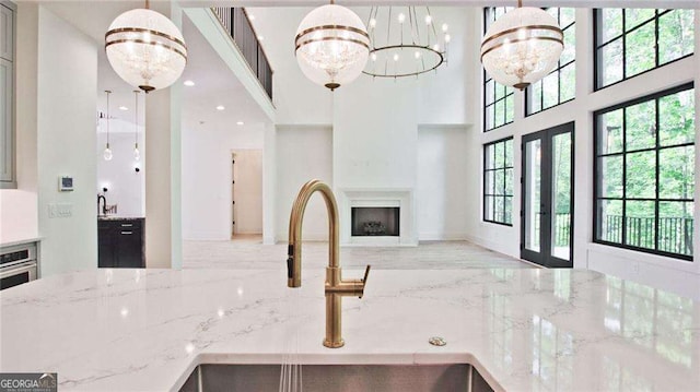 kitchen featuring light stone countertops, sink, hanging light fixtures, and a notable chandelier