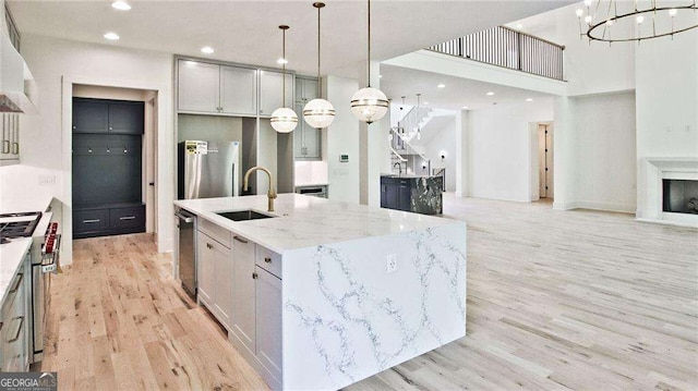 kitchen featuring sink, decorative light fixtures, a kitchen island with sink, and high end stove