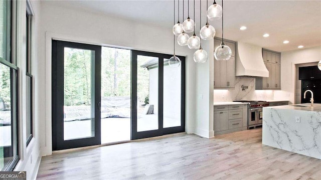 kitchen with gray cabinets, double oven range, decorative light fixtures, and custom exhaust hood