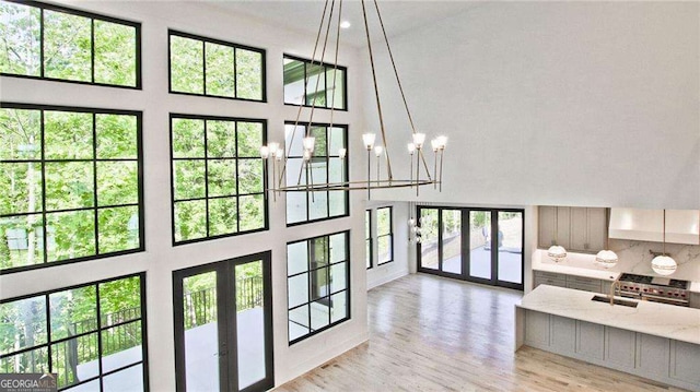 entryway with light hardwood / wood-style floors, sink, a towering ceiling, and a chandelier