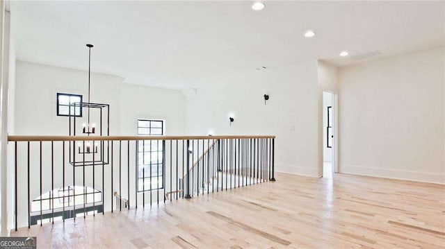 empty room featuring an inviting chandelier and light wood-type flooring