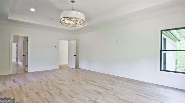 unfurnished room featuring a tray ceiling and light wood-type flooring