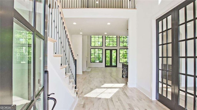 entryway featuring french doors, a towering ceiling, and light hardwood / wood-style floors