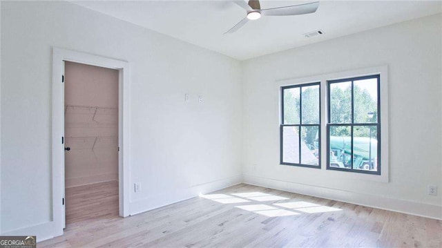 empty room with ceiling fan and light hardwood / wood-style flooring