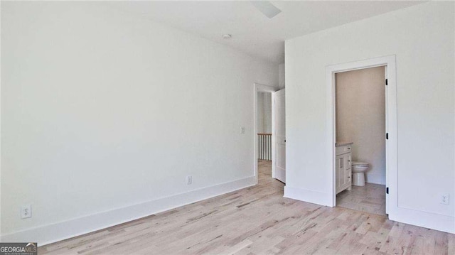 unfurnished bedroom featuring ensuite bathroom and light wood-type flooring