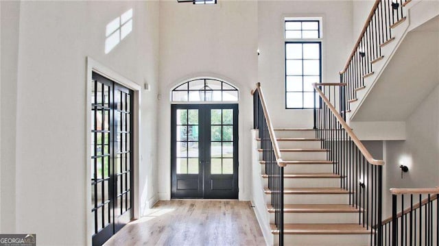 entrance foyer featuring a high ceiling, french doors, light wood-type flooring, and a wealth of natural light