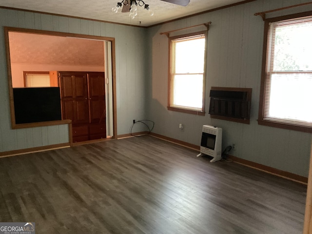 unfurnished living room featuring ceiling fan, a wealth of natural light, hardwood / wood-style floors, and heating unit