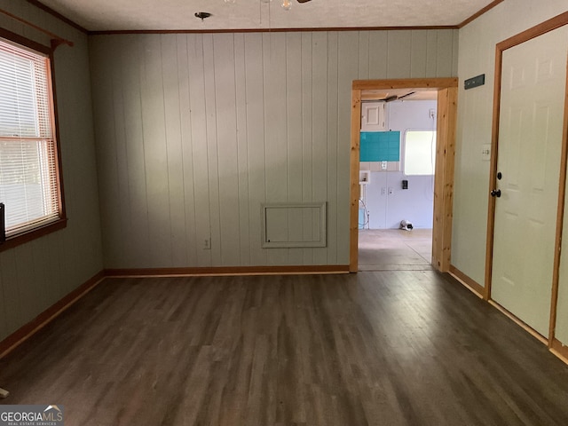 spare room featuring ceiling fan, ornamental molding, wood walls, and dark hardwood / wood-style floors